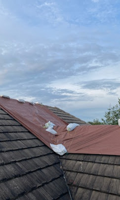 Tile roof secured with red emergency tarp and sandbag hold-down system