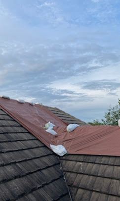 Tile roof secured with red emergency tarp and sandbag hold-down system