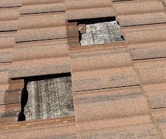 Broken roof tiles with exposed underlayment before emergency tarp install