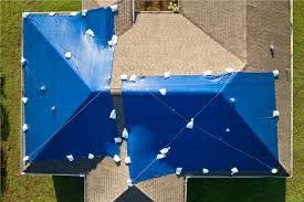 Aerial view of full-roof blue emergency tarp install with sandbag securement system