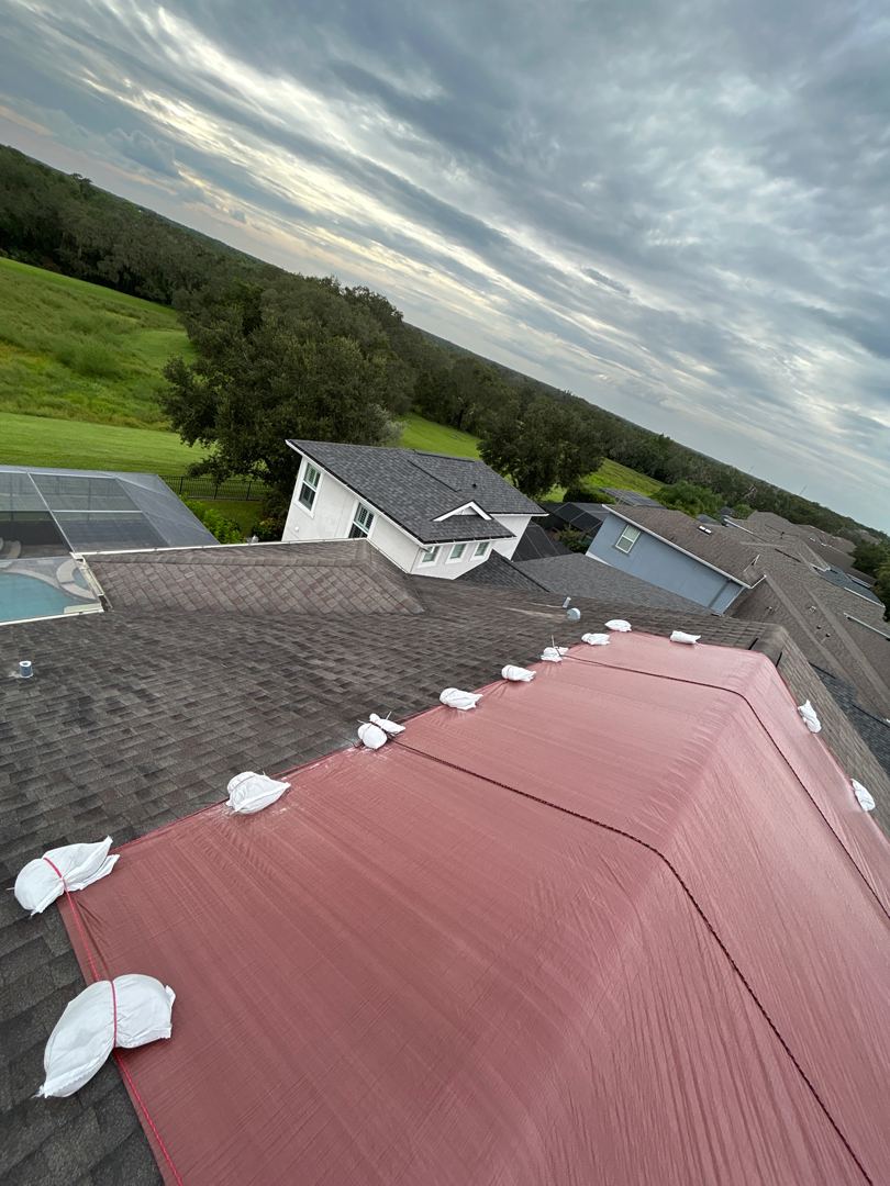 Side view of red emergency tarp install with sandbag hold-downs at sunset