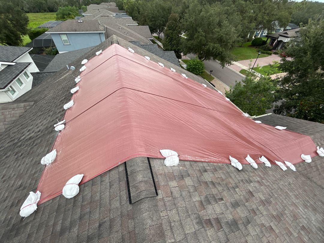 Wide aerial of completed red emergency tarp install on Tampa Bay home