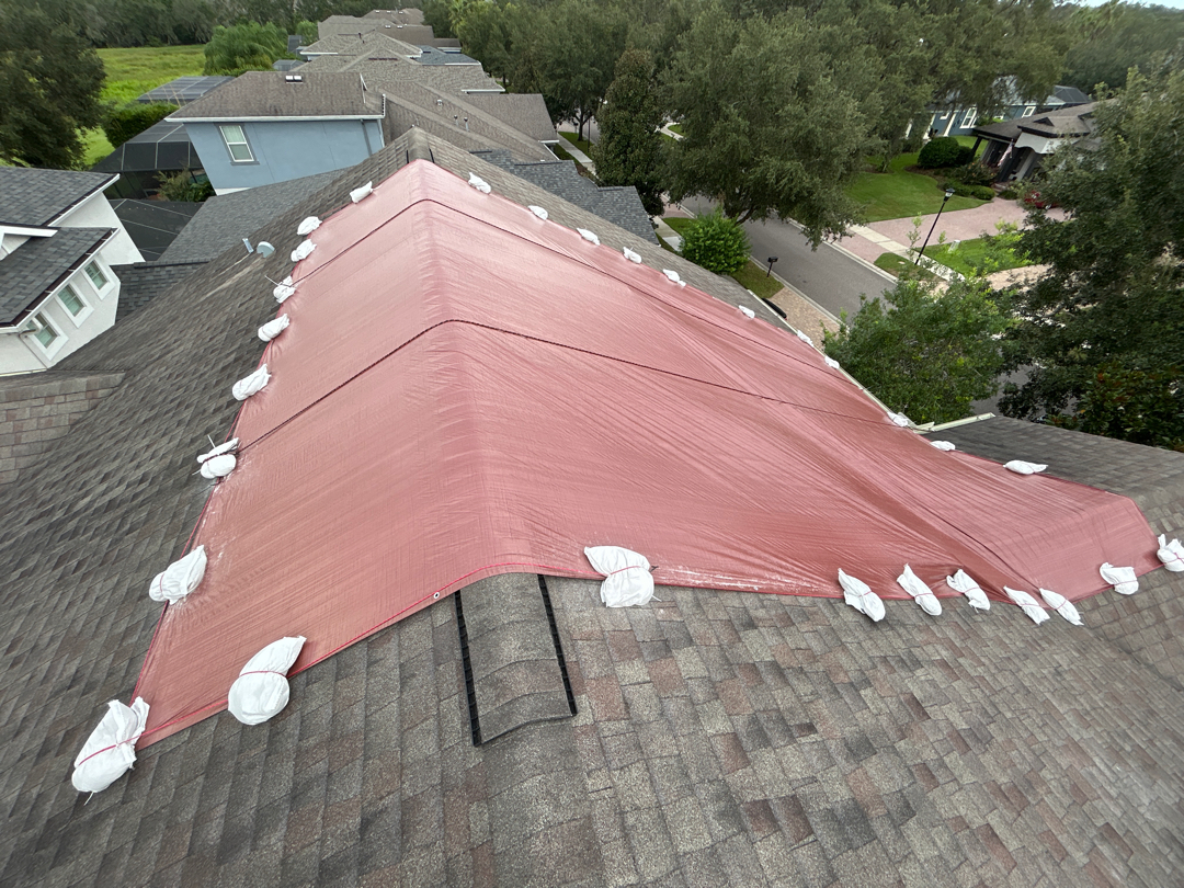 Wide aerial of completed red emergency tarp install on Tampa Bay home