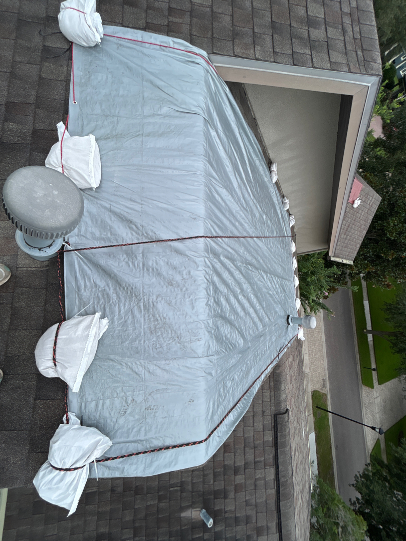 Aerial view of white emergency tarp install with sandbag perimeter on Tampa Bay shingle roof