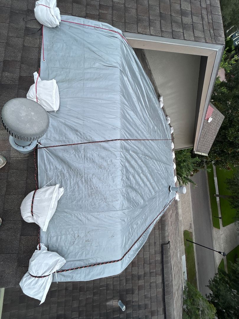 Aerial view of white emergency tarp install with sandbag perimeter on Tampa Bay shingle roof