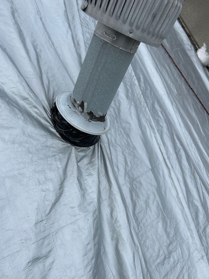 Close-up of vent pipe penetration sealed with weatherproof boot through emergency tarp